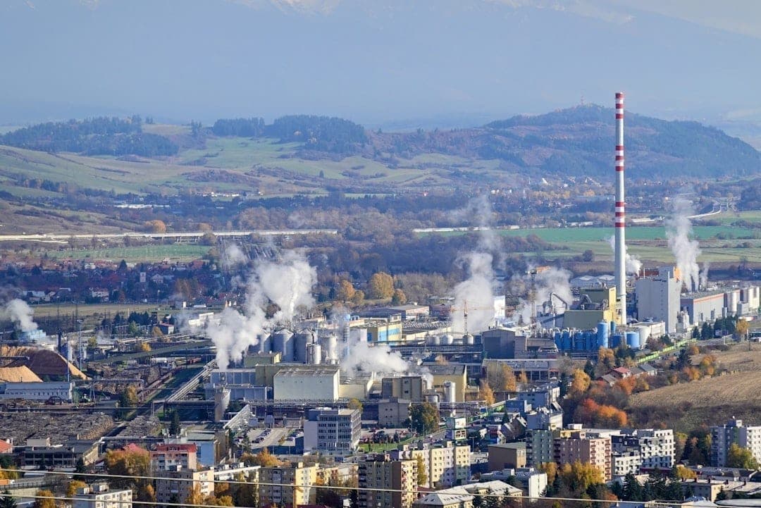 Industriellt komplex med rykande skorstenar, som representerar den typ av anläggning som kräver multiparameter VOC-, NO2- och CO-övervakning