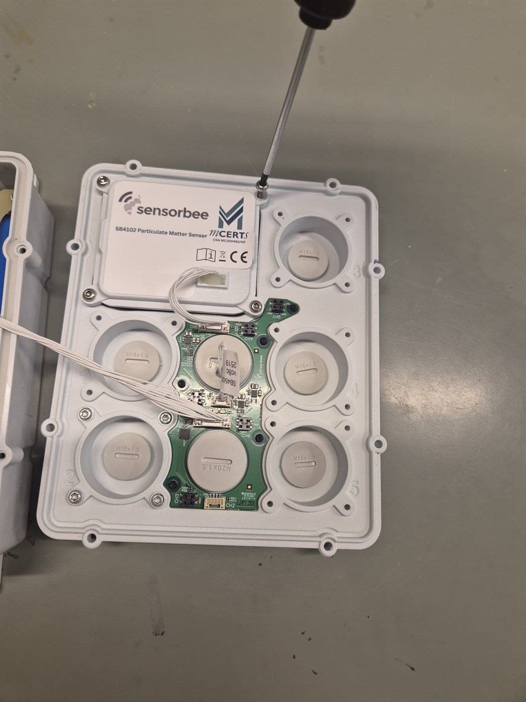 Unscrewing the four particle sensor screws with a T10 screwdriver