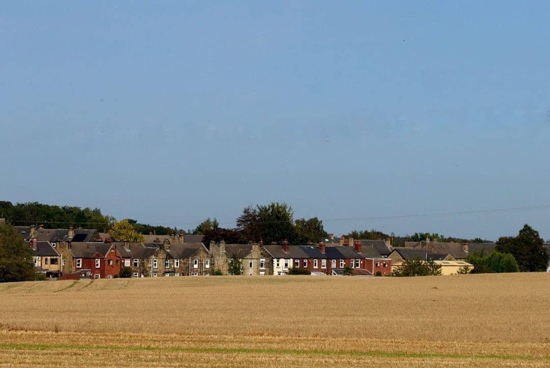 Green field bordered by residential houses — a typical greenfield site at the edge of an existing settlement