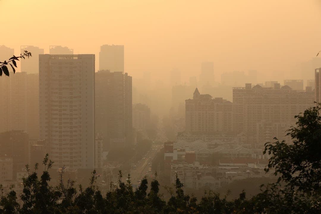 City skyline shrouded in smog haze, illustrating the urban air pollution that dense sensor networks help monitor and reduce