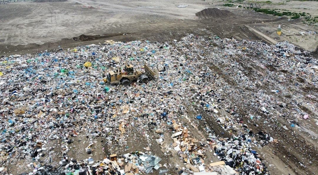 Aerial view of heavy machinery compacting waste at a landfill site, showing the scale of municipal waste operations that generate harmful gas emissions